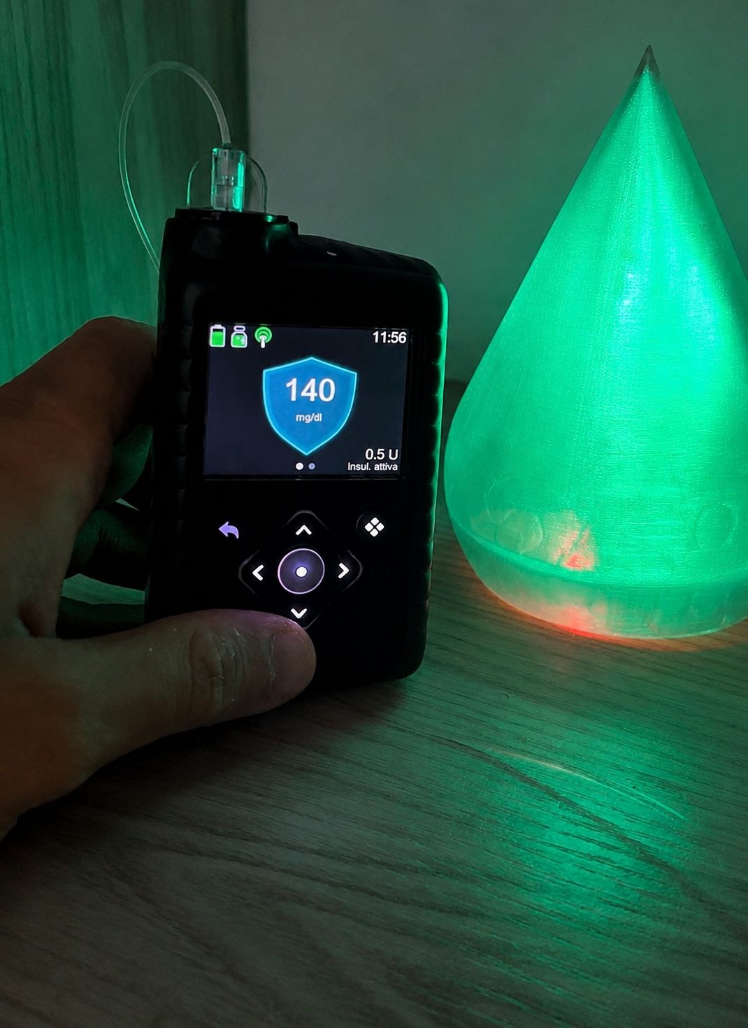 Lampada a goccia che si illumina di verde accanto a un microinfusore che segna 140 mg/dl